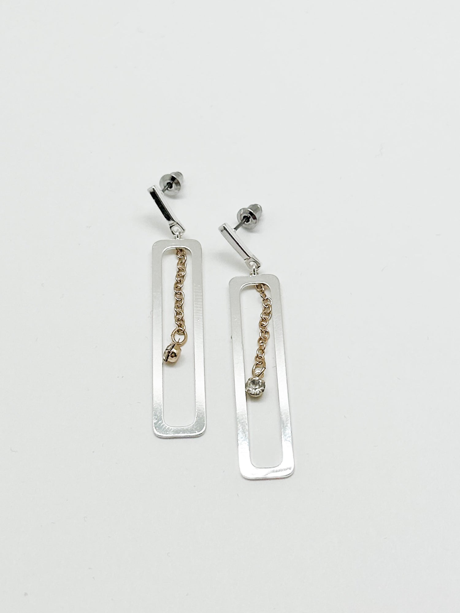 Shelby earring. silver dangly rectangle with a gold chain with tiny crystal in center. 