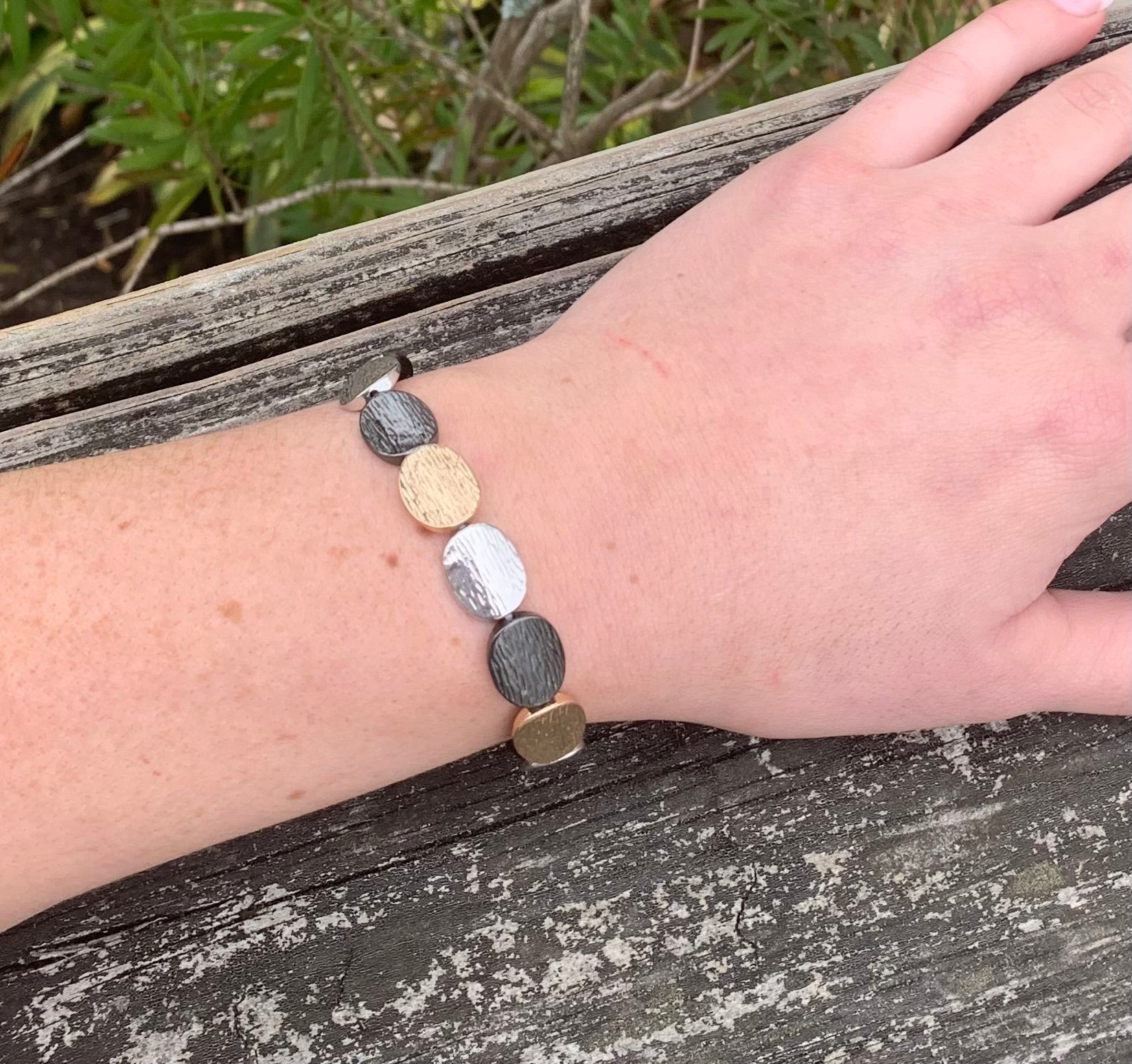 Gold, silver, and black metal oval bracelet  on model 